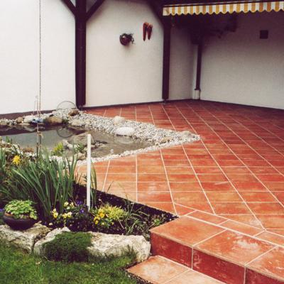 Terrasse mit roten Verlegeplatten diagonal verlegt.